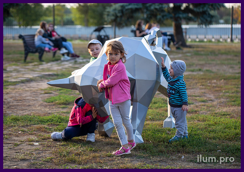 Дети играют с полигональной скульптурой быка из металла в парке