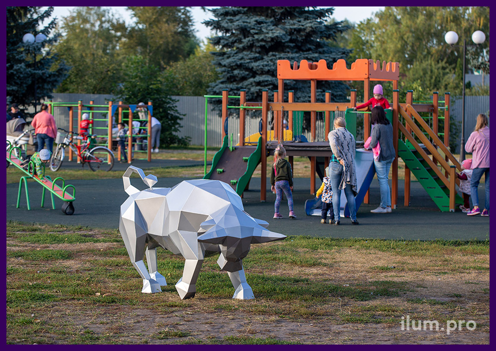 Серебристый бык полигональный из стали у детской площадки в парке