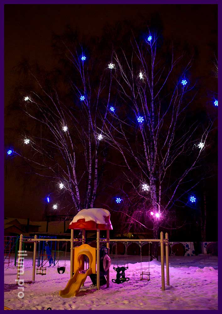 Украшение деревьев на Новый год светящимися снежинками и разноцветными прожекторами