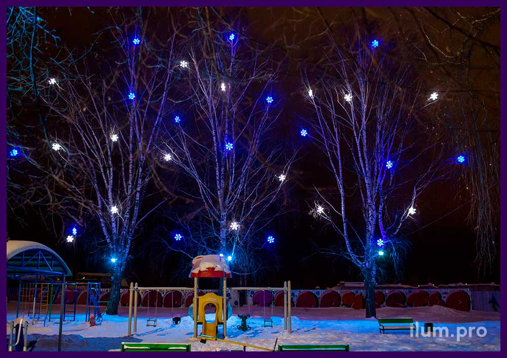 Светодиодные снежинки белого и синего цвета и прожекторы RGB на деревьях