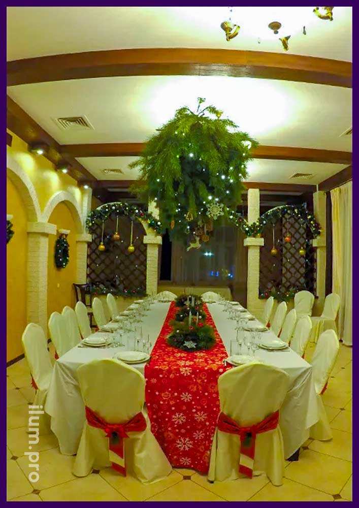 Новогоднее украшение интерьера ресторана хвойными декорациями и красными тканями