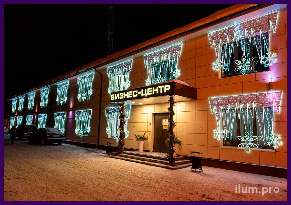 Новогодние консоли белого цвета на фасаде бизнес-центра, декор в форме сосулек со снежинками