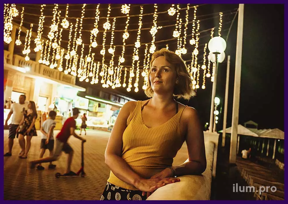 Девушка фотографируется на фоне светодиодных гирлянд на набережной