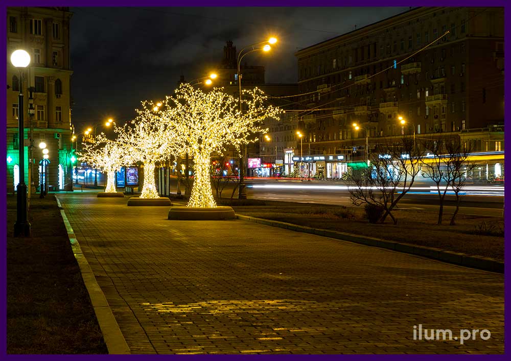 Светящиеся деревья из алюминия с гирляндами на тротуаре - декорации из металла и иллюминации