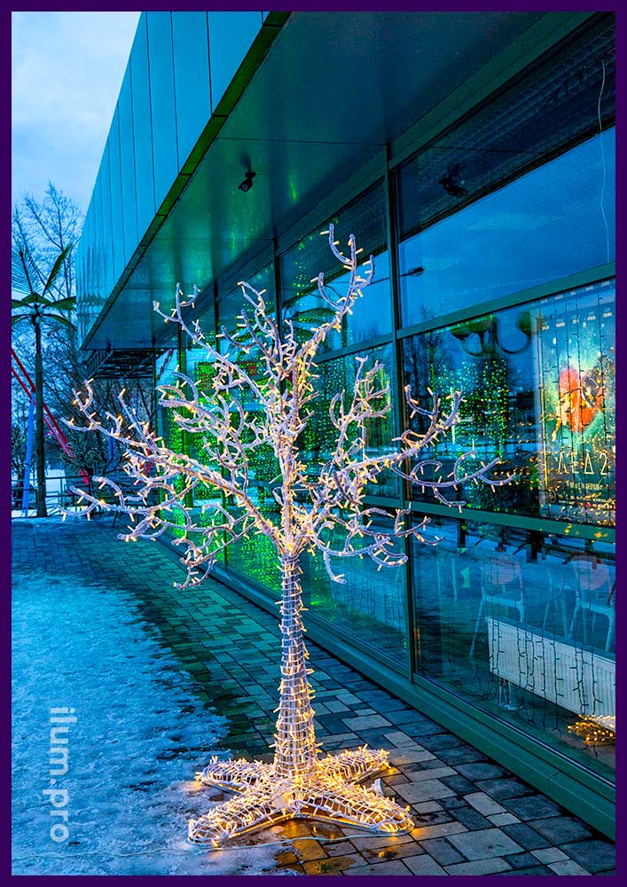 Светящееся металлическое дерево с гирляндами у здания