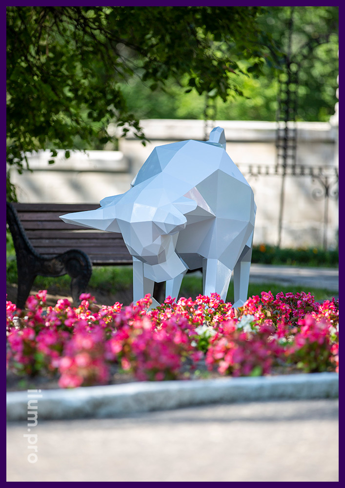 Белая полигональная скульптура металлического быка в парке на газоне