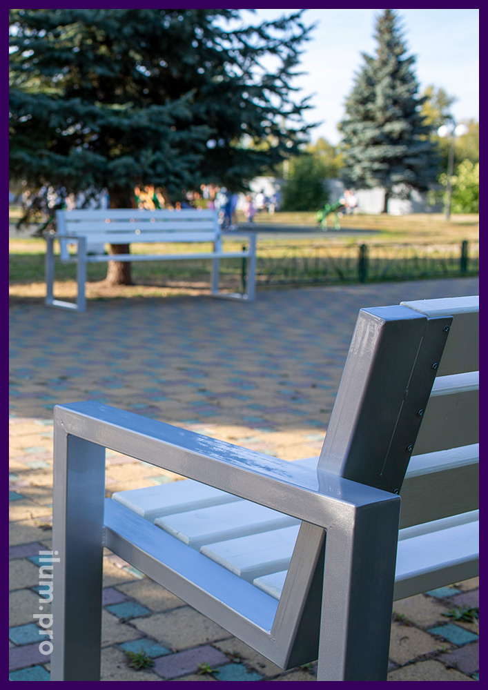 Строгие скамейки серебристого цвета в парке из стали и дерева