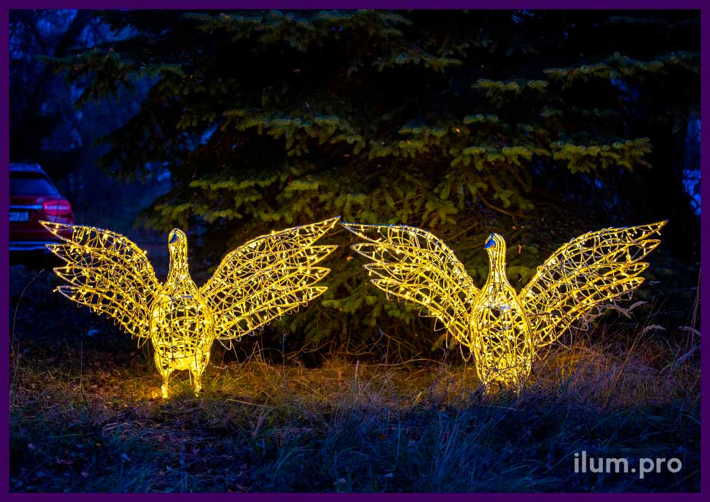 Два светодиодных гуся рядом с ёлками в парке на Новый год