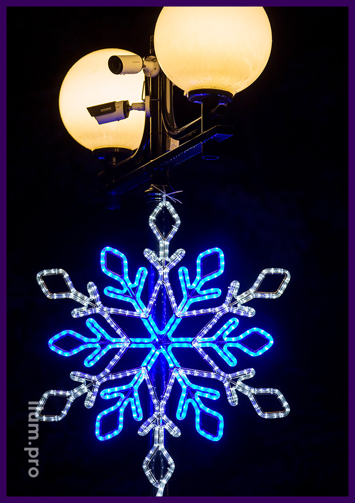 Оформление фонаря в парке светодиодными снежинками белого и синего цвета на Новый год