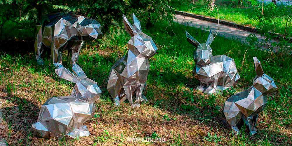 Полигональные фигуры зайцев и медведя из металла в парке