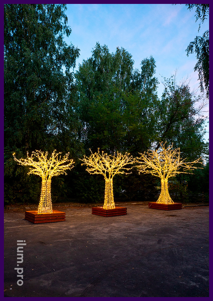 Три дерева разных размеров из металлических труб и светодиодных гирлянд