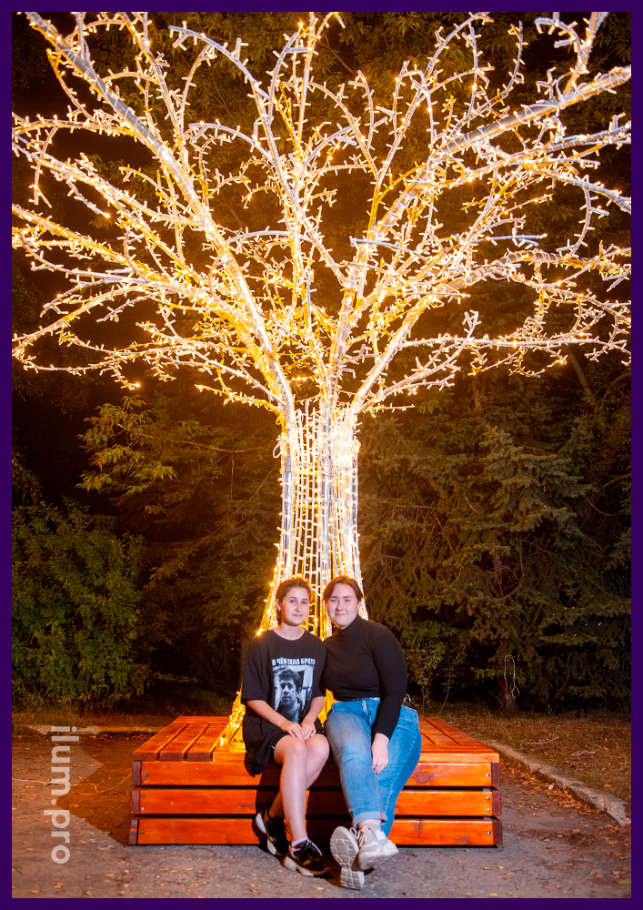 Праздничная фотозона из металлического каркаса и светодиодных гирлянд в форме дерева со скамейкой