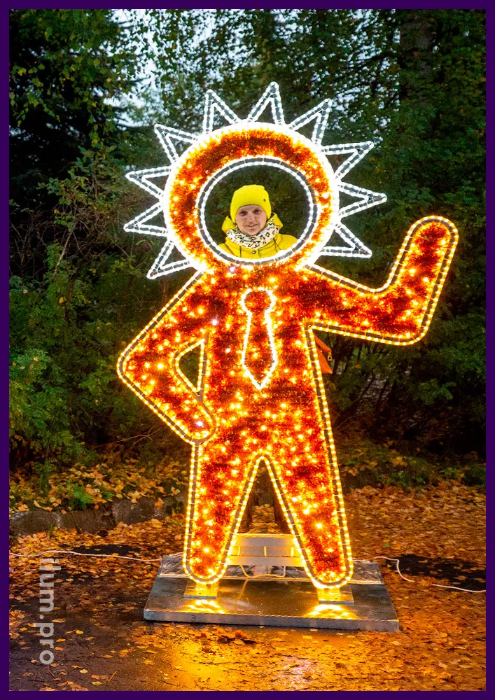 Золотая фигура инопланетянина в галстуке с подсветкой гирляндами и блестящей мишурой