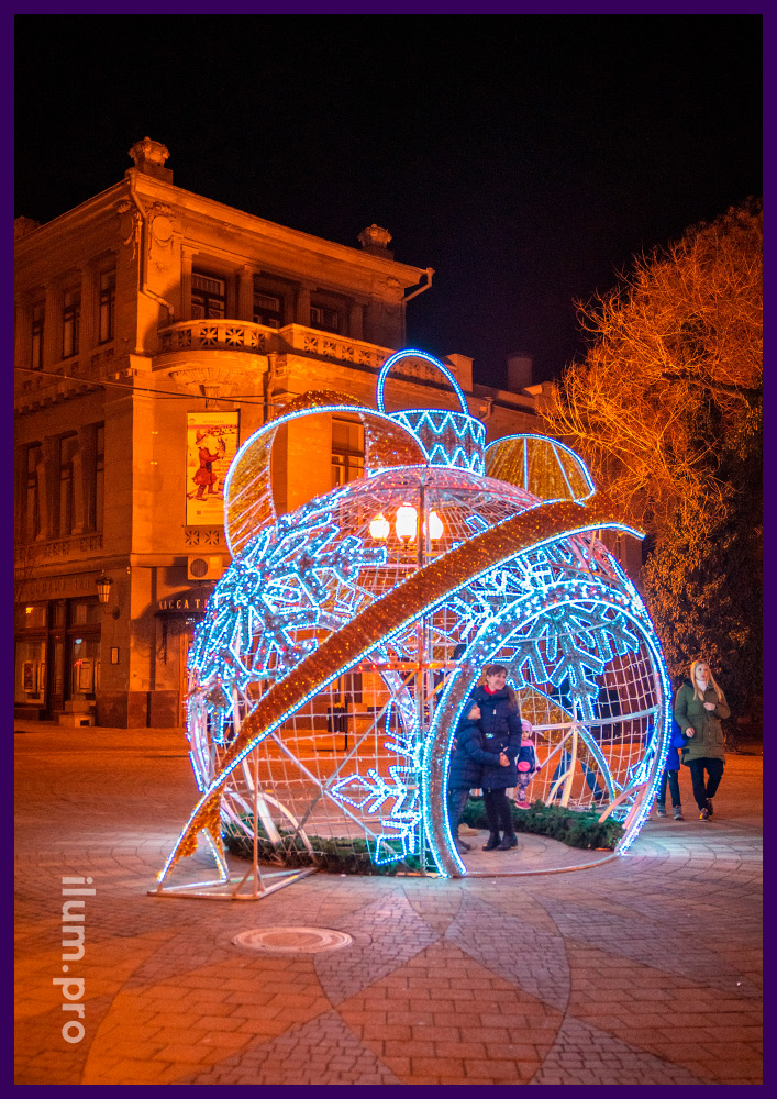 Украшение площади в Крыму новогодними декорациями с гирляндами - шар в форме ёлочной игрушки со снежинками