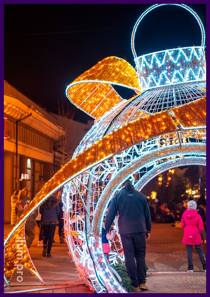 Новогодние декорации в Крыму на городской площади, светящийся шар-арка с золотым бантом и гирляндами