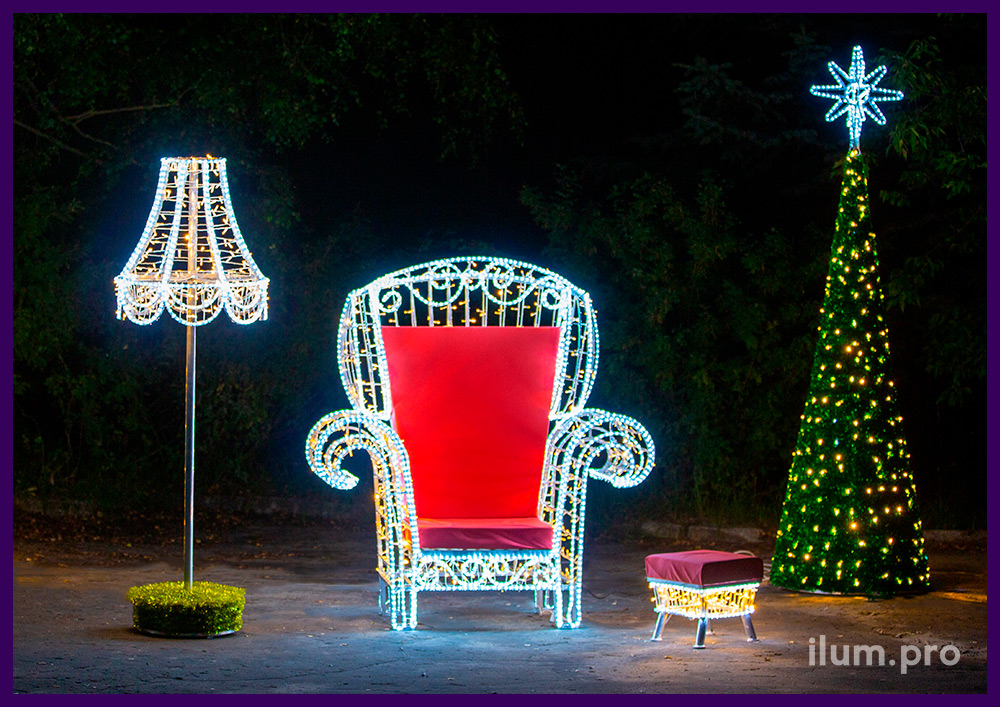 Новогодняя фотозона с красным креслом из гирлянд, торшером и пуфиком, а также ёлками из мишуры