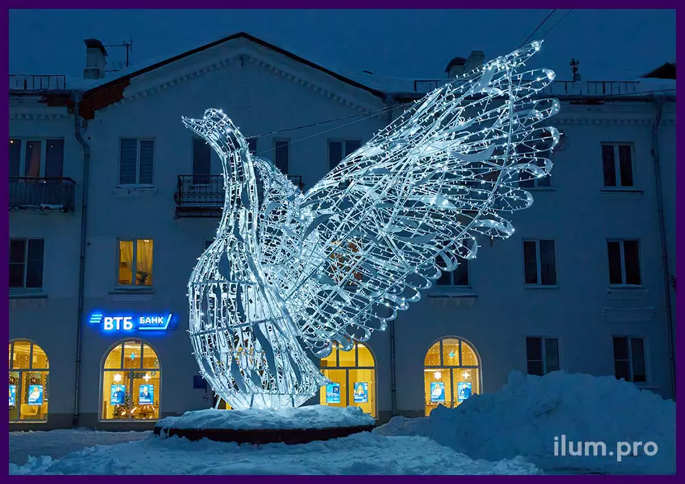 Светящаяся фигура большой белой птицы с уличными гирляндами на городской площади