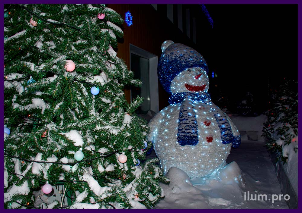 Светящаяся фигура снеговика и уличные гирлянды на ёлках и фасаде здания в Надыме на Новый год