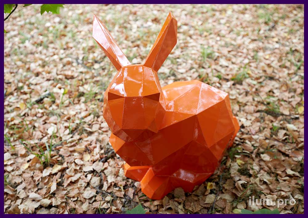 Металлическая полигональная скульптура оранжевого сигнального зайца в парке