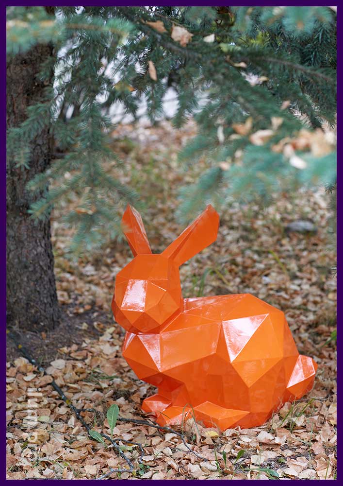 Металлическая полигональная скульптура оранжевого зайца с полым каркасом в городском парке