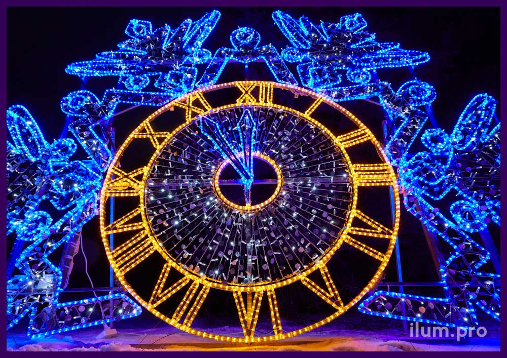Новогодние декорации в городском парке - часы с гирляндами и короной в форме снежинки