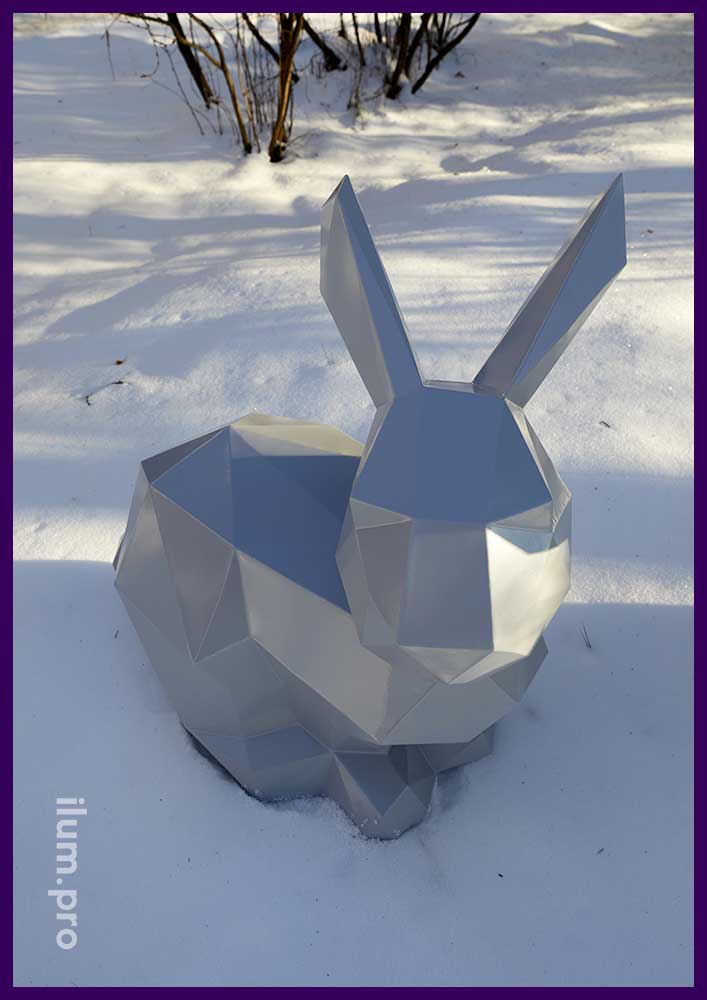 Металлическая полигональная скульптура зайца серого цвета на снегу