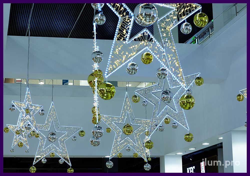 Украшение интерьера торгового центра на Новый год светящимися звёздами с ёлочными шарами и гирляндами