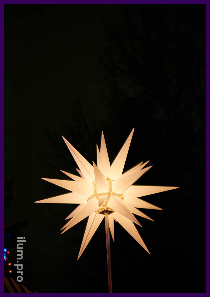 Звезда гернгута тёпло-белого цвета над вертепом католического храма на Рождество