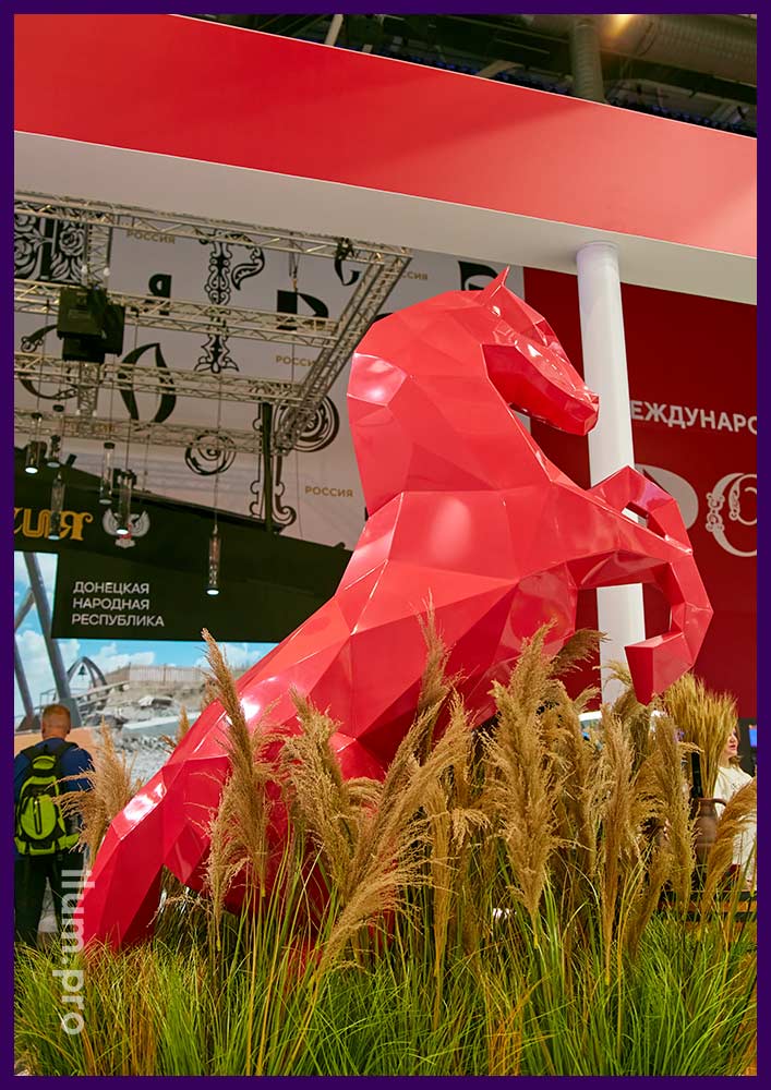 Металлическая скульптура коня красного цвета - оформление выставочного стенда на ВДНХ