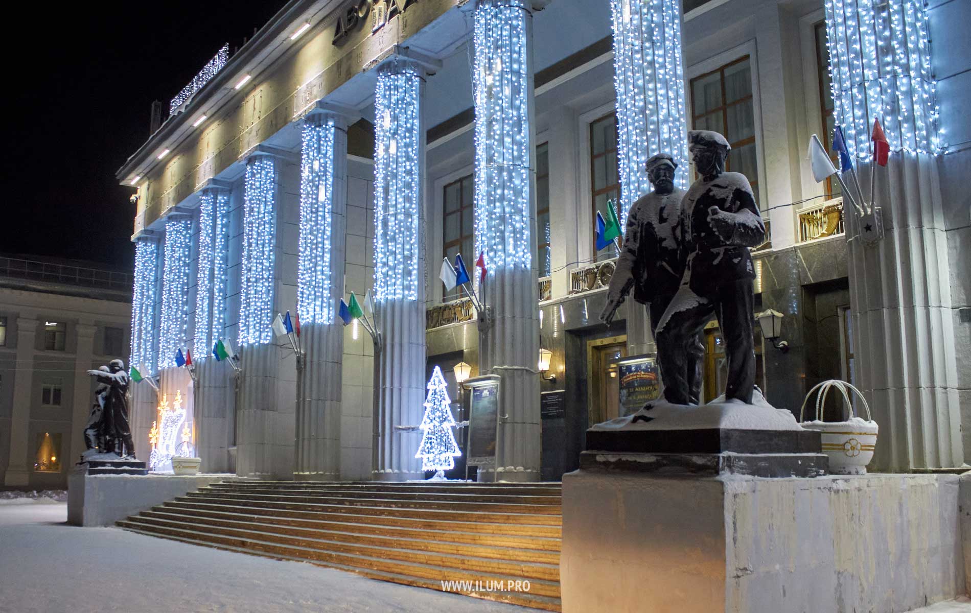 Новогодняя подсветка фасада здания дождями белого цвета и световыми фигурами